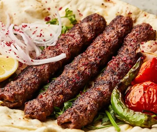 Türkiye’nin en önemli gastronomi değerlerinden biri olan Adana Kebap, yıllardır geleneksel tarifleriyle sofralarda yer alırken son dönemde değişen restoran anlayışıyla birlikte farklı sunum teknikleriyle de dikkat çekmeye başladı. Özellikle sosyal medya kullanımının artması, restoranların görsel açıdan daha dikkat çekici tabaklar hazırlamasına neden oldu. Böylece klasik kebap kültürü korunurken modern gastronomi dünyasına uygun yeni sunum trendleri ortaya çıktı. Konulu bir haber görseli.
