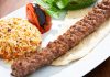 Türkiye’nin en köklü yemek kültürlerinden biri olan Urfa Kebap, kendine özgü aroması ve pişirme tekniğiyle kebap çeşitleri arasında özel bir yere sahip bulunuyor. Güneydoğu Anadolu mutfağının önemli temsilcilerinden biri olan bu lezzet, özellikle baharat dengesi ve etin doğal tadını ön plana çıkaran yapısıyla dikkat çekiyor. Acı oranının daha düşük olması nedeniyle geniş bir damak zevkine hitap eden Urfa Kebap, yıllardır hem yerel halkın hem de turistlerin yoğun ilgi gösterdiği yemekler arasında yer alıyor. Konulu bir haber görseli.