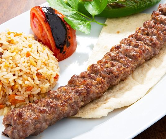 Türkiye’nin en köklü yemek kültürlerinden biri olan Urfa Kebap, kendine özgü aroması ve pişirme tekniğiyle kebap çeşitleri arasında özel bir yere sahip bulunuyor. Güneydoğu Anadolu mutfağının önemli temsilcilerinden biri olan bu lezzet, özellikle baharat dengesi ve etin doğal tadını ön plana çıkaran yapısıyla dikkat çekiyor. Acı oranının daha düşük olması nedeniyle geniş bir damak zevkine hitap eden Urfa Kebap, yıllardır hem yerel halkın hem de turistlerin yoğun ilgi gösterdiği yemekler arasında yer alıyor. Konulu bir haber görseli.