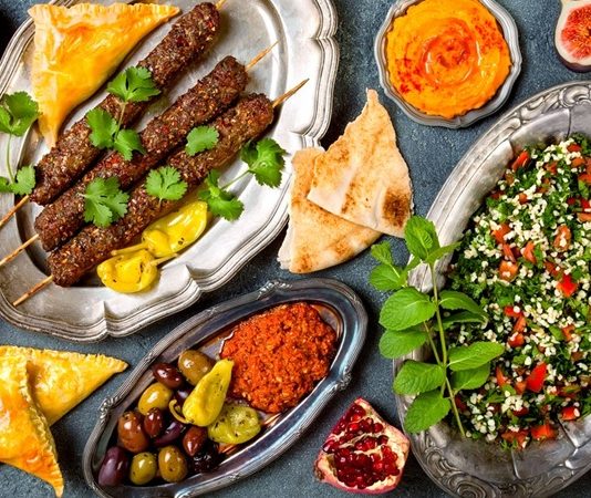 Kebap, Türk mutfağının en güçlü gastronomik değerlerinden biri olarak hem yerli hem de yabancı turistlerin ilgisini çekmeye devam ediyor. Son yıllarda lezzet odaklı seyahatlerin artmasıyla birlikte gastronomi turizmi içerisinde kebabın önemi daha da belirgin hale gelirken, farklı şehirlerde sunulan yöresel kebap çeşitleri ziyaretçilere kültürel ve damak zevkine hitap eden özel deneyimler sunuyor. Bu gelişim, turizm sektörüne ekonomik katkı sağlarken Türk mutfağının uluslararası alandaki tanınırlığını da artırıyor. Konulu bir haber görseli.