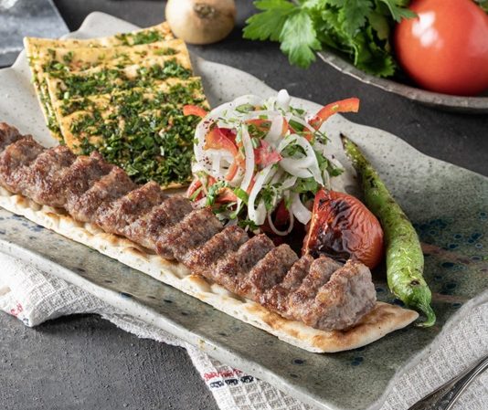 Kebap Menü Çeşitliliği, Türk mutfağının zengin gastronomi mirasını yansıtan en önemli unsurlardan biri olarak öne çıkıyor. Türkiye'nin farklı bölgelerinde gelişen kebap kültürü, zaman içinde yalnızca et çeşitleriyle değil, garnitürlerden mezelere, pişirme tekniklerinden sunum anlayışına kadar geniş bir yelpazeye ulaştı. Günümüzde birçok restoran, farklı damak tatlarına hitap edebilmek için klasik tariflerin yanında modern yorumlara da menülerinde yer veriyor. Konulu bir haber görseli.