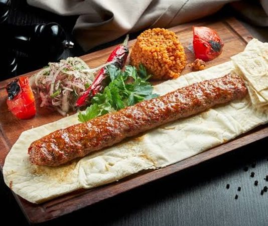 Kebapta Lüks Sunum Deneyimi, son yıllarda gastronomi sektöründe dikkat çeken yeniliklerden biri olarak öne çıkıyor. Geleneksel kebap kültürü, modern sunum anlayışıyla birleşerek restoranlarda farklı bir deneyime dönüşüyor. Artık müşteriler yalnızca lezzetli bir yemek yemekle yetinmiyor; kullanılan tabaklardan servis ekipmanlarına, masa düzeninden sunum tekniklerine kadar her ayrıntının özenle hazırlanmasını bekliyor. Bu değişim, özellikle üst segment restoranlarda hizmet anlayışını yeniden şekillendiriyor. Konulu bir haber görseli.