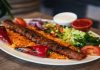 Kebap, Türkiye’nin gastronomi kimliğini oluşturan en güçlü lezzetlerden biri olarak şehirler arasında yoğun bir rekabetin merkezinde yer alıyor. Her şehrin kendine özgü pişirme tekniği, baharat kullanımı ve sunum anlayışı, kebap kültürünü sadece bir yemek olmaktan çıkarıp aynı zamanda bir gastronomi yarışına dönüştürüyor. Özellikle son yıllarda artan restoran yatırımları ve gastronomi turizmi sayesinde şehir bazlı kebap rekabeti daha görünür hale gelmiş durumda. Konulu bir haber görseli.