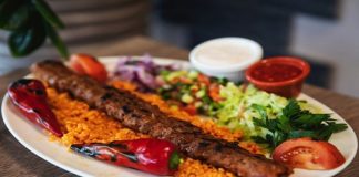 Kebap, Türkiye’nin gastronomi kimliğini oluşturan en güçlü lezzetlerden biri olarak şehirler arasında yoğun bir rekabetin merkezinde yer alıyor. Her şehrin kendine özgü pişirme tekniği, baharat kullanımı ve sunum anlayışı, kebap kültürünü sadece bir yemek olmaktan çıkarıp aynı zamanda bir gastronomi yarışına dönüştürüyor. Özellikle son yıllarda artan restoran yatırımları ve gastronomi turizmi sayesinde şehir bazlı kebap rekabeti daha görünür hale gelmiş durumda. Konulu bir haber görseli.